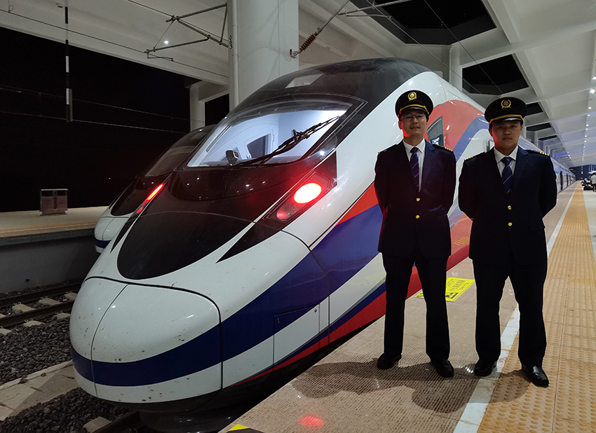 劉銀能（右一）與中國(guó)師父鄔俊鴻在動(dòng)車組前合影。受訪者供圖