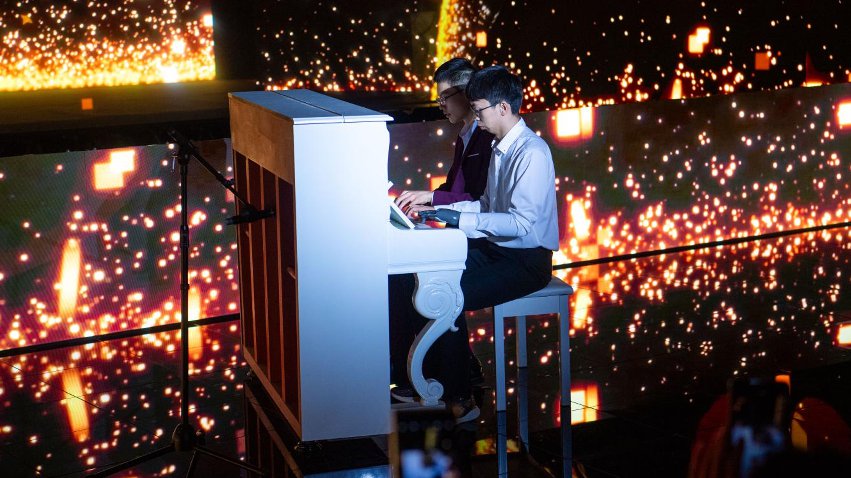 智能仿生手使用者古月與少年鋼琴家舒海峰合奏。主辦方供圖